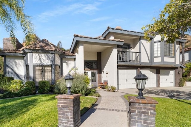 english style home featuring a garage, concrete driveway, a balcony, stucco siding, and a front yard