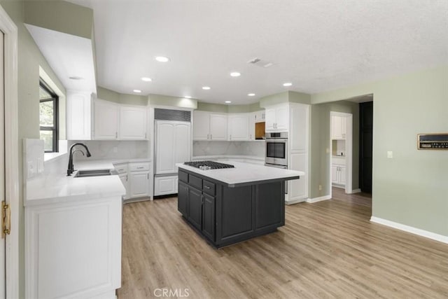 kitchen with stainless steel appliances, a sink, light countertops, and white cabinets