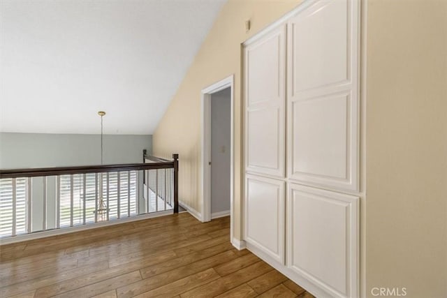 hall with vaulted ceiling, baseboards, and wood finished floors