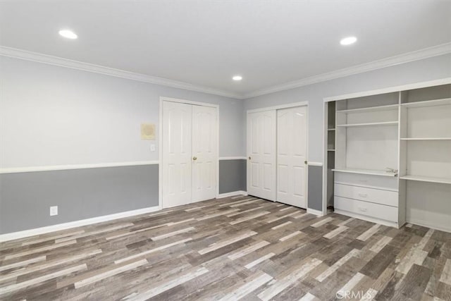 unfurnished bedroom with baseboards, ornamental molding, wood finished floors, multiple closets, and recessed lighting