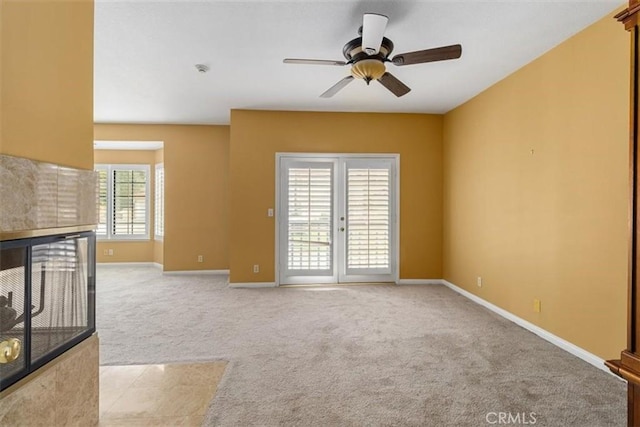 unfurnished living room featuring baseboards, light carpet, ceiling fan, and a tiled fireplace