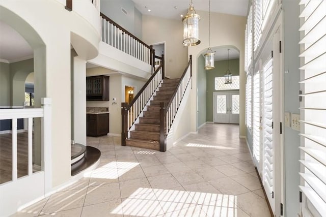 foyer with stairs, a high ceiling, light tile patterned flooring, and baseboards