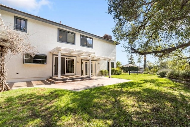 rear view of property featuring a patio, a chimney, stucco siding, a lawn, and a pergola