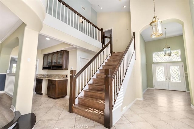 foyer with arched walkways, french doors, a towering ceiling, and visible vents