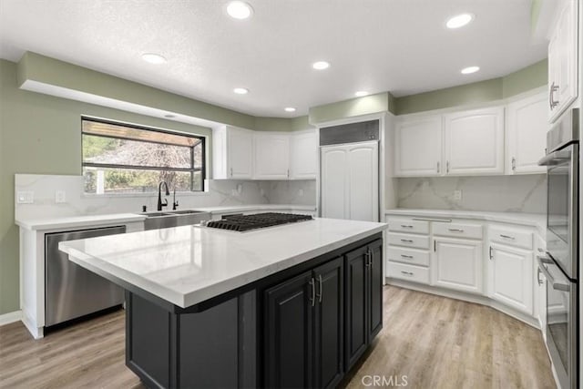 kitchen featuring white cabinetry, a kitchen island, appliances with stainless steel finishes, and a sink