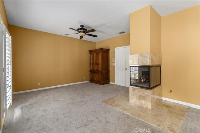 unfurnished living room featuring light carpet, a fireplace, a ceiling fan, visible vents, and baseboards