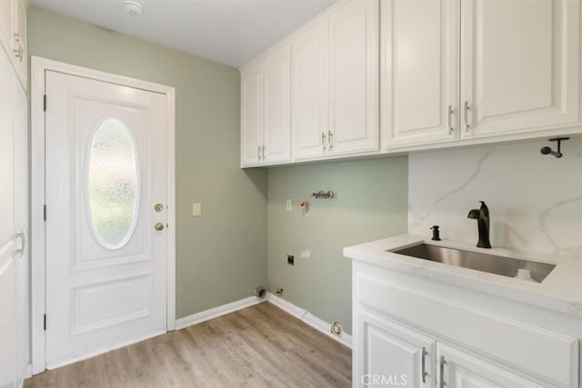 washroom with cabinet space, light wood finished floors, hookup for a gas dryer, hookup for a washing machine, and a sink