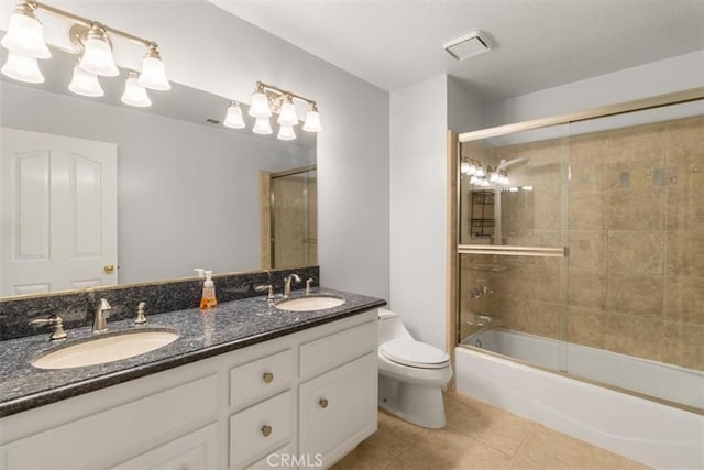 full bathroom with bath / shower combo with glass door, a sink, toilet, and tile patterned floors