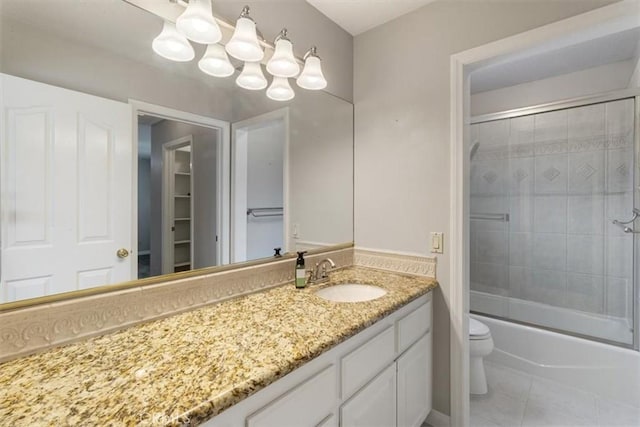 bathroom with toilet, tile patterned flooring, bath / shower combo with glass door, and vanity