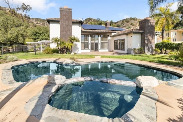 view of pool with a pool with connected hot tub, fence, and a lawn