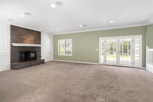 unfurnished living room with ornamental molding, french doors, a brick fireplace, and carpet