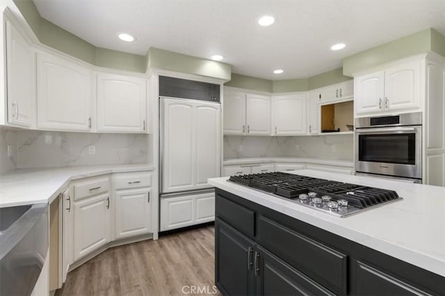 kitchen with light wood-style flooring, appliances with stainless steel finishes, light countertops, dark cabinetry, and white cabinetry