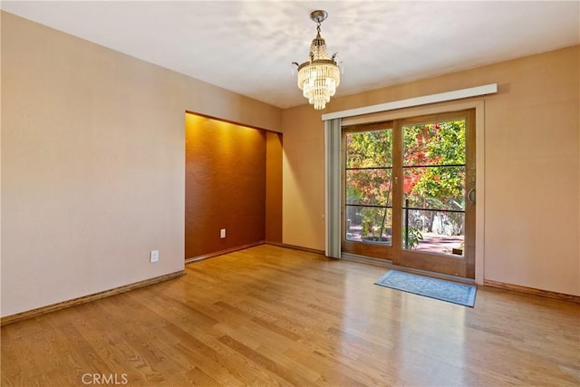 unfurnished room featuring light hardwood / wood-style floors and an inviting chandelier