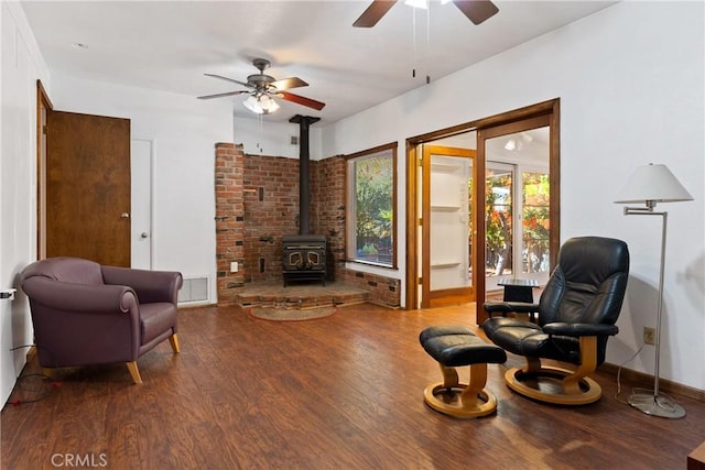 living room featuring a wood stove, ceiling fan, and hardwood / wood-style flooring