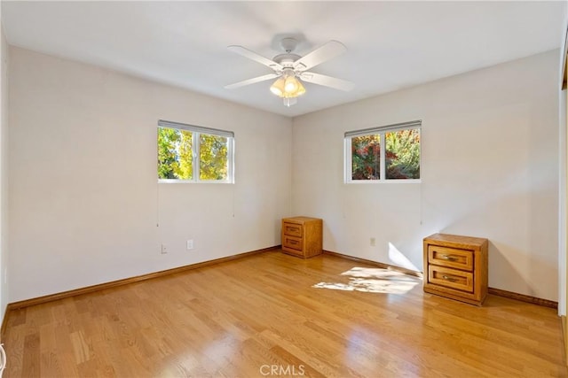 spare room with ceiling fan, a healthy amount of sunlight, and light hardwood / wood-style floors