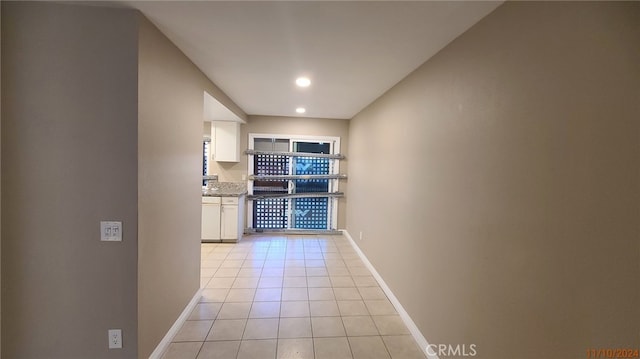 corridor with light tile patterned floors and baseboards