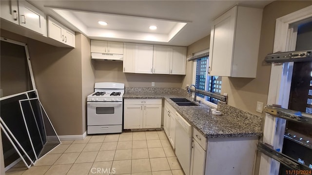 kitchen with dark stone countertops, white cabinetry, sink, and white appliances