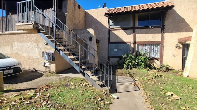 exterior space featuring stucco siding, stairway, and a tiled roof