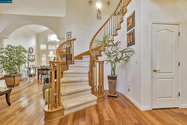 staircase with hardwood / wood-style flooring and high vaulted ceiling