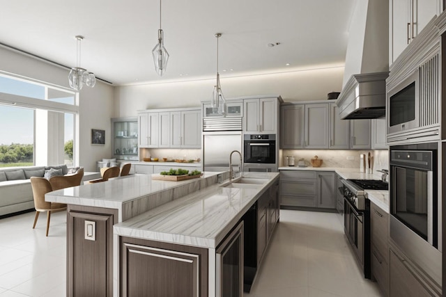 kitchen featuring pendant lighting, sink, appliances with stainless steel finishes, gray cabinetry, and a large island with sink