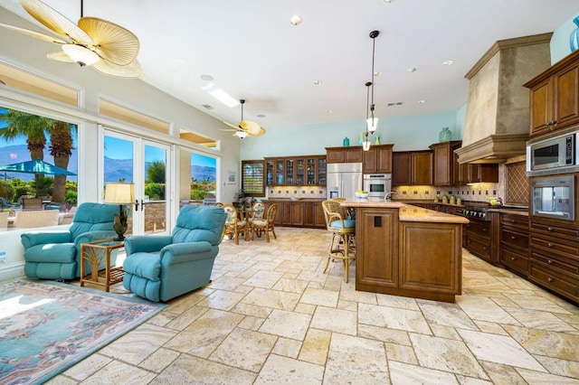 kitchen featuring pendant lighting, a breakfast bar area, a center island, built in appliances, and light stone counters