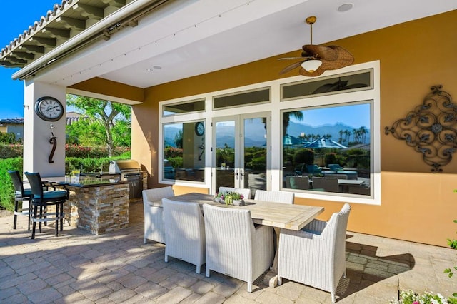 view of patio featuring french doors, an outdoor kitchen, grilling area, a bar, and ceiling fan