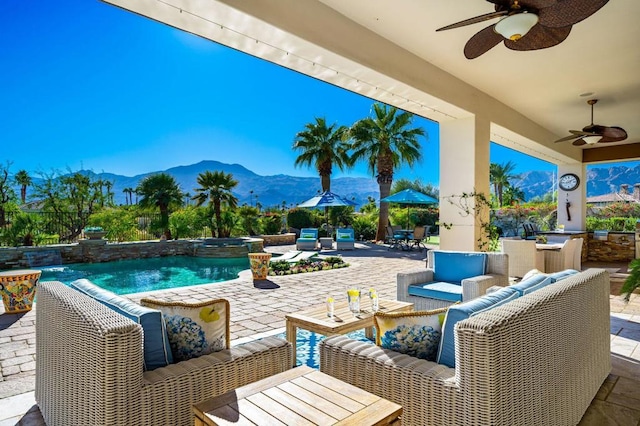 view of patio featuring a bar, an outdoor hangout area, ceiling fan, a pool with hot tub, and a mountain view