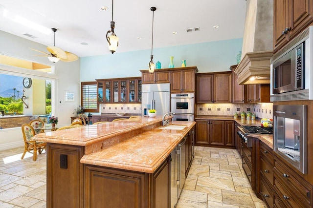 kitchen featuring appliances with stainless steel finishes, a breakfast bar, an island with sink, and decorative backsplash