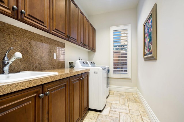 clothes washing area featuring separate washer and dryer, sink, and cabinets