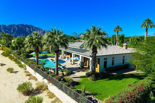 back of property featuring a mountain view, a yard, and a patio area