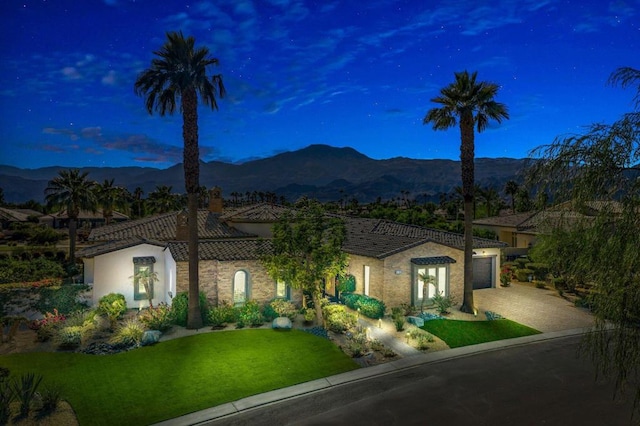 view of front of house featuring a mountain view, a garage, and a lawn