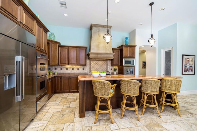 kitchen with built in appliances, decorative light fixtures, and a kitchen island