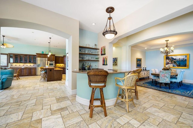 kitchen with a kitchen bar, hanging light fixtures, ornamental molding, kitchen peninsula, and stainless steel appliances