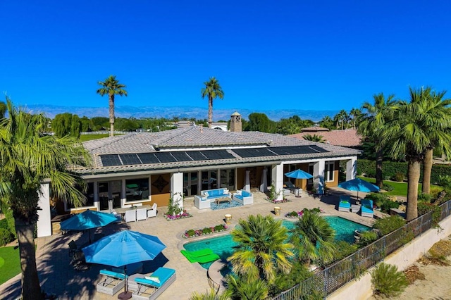 back of house featuring an outdoor living space, a fenced in pool, a patio area, and solar panels