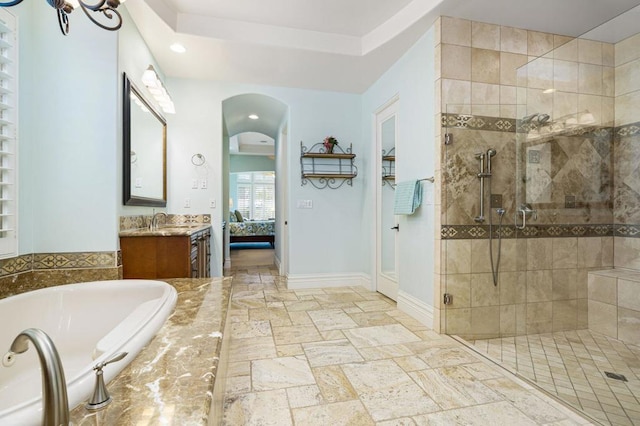 bathroom with vanity, independent shower and bath, and a raised ceiling