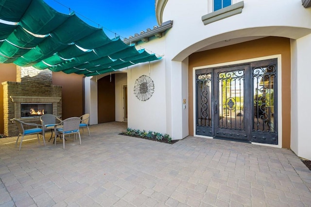 doorway to property featuring exterior fireplace and a patio