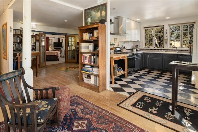 kitchen featuring gray cabinetry, sink, wall chimney exhaust hood, light hardwood / wood-style flooring, and stainless steel range with gas stovetop