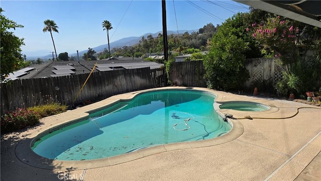 3930 Ironwood St, San Bernardino, CA 92404 - view of swimming pool featuring a pool with connected hot tub, a mountain view, and a fenced backyard