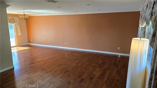 empty room featuring crown molding, dark hardwood / wood-style flooring, and a notable chandelier