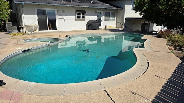 view of swimming pool with an in ground hot tub, a patio area, grilling area, and cooling unit