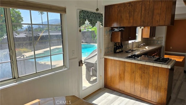 kitchen featuring a mountain view, sink, tasteful backsplash, tile counters, and stainless steel gas cooktop