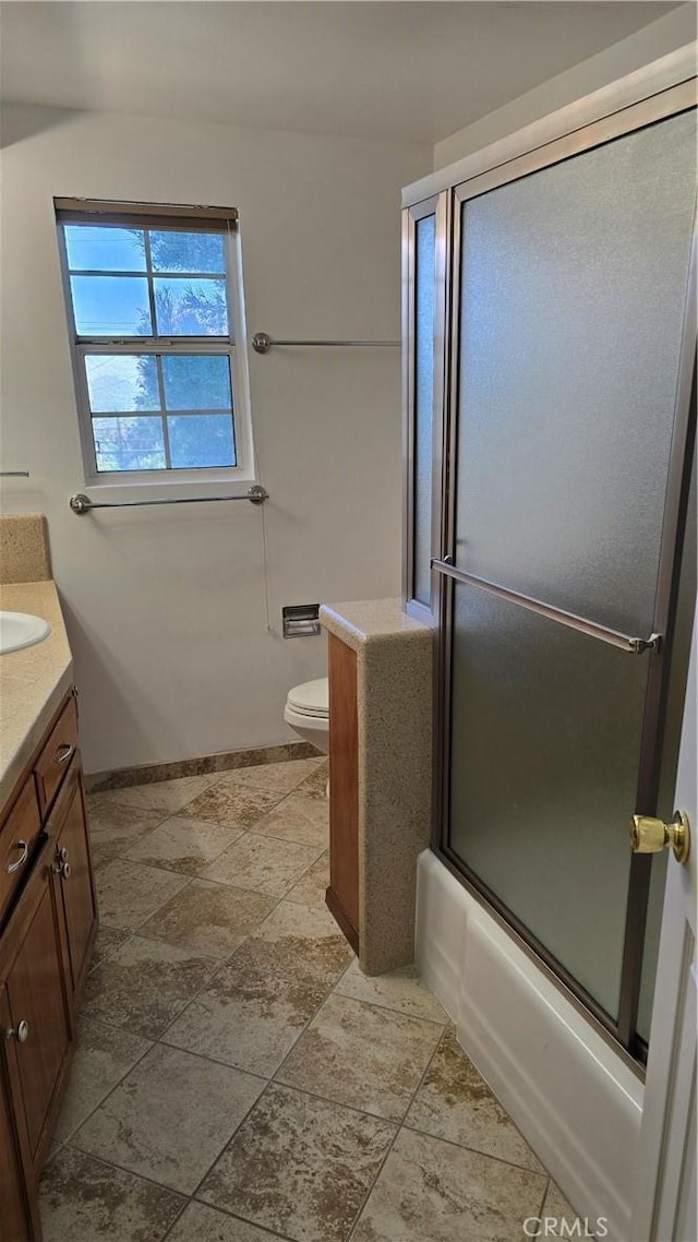 full bathroom featuring combined bath / shower with glass door, vanity, and toilet