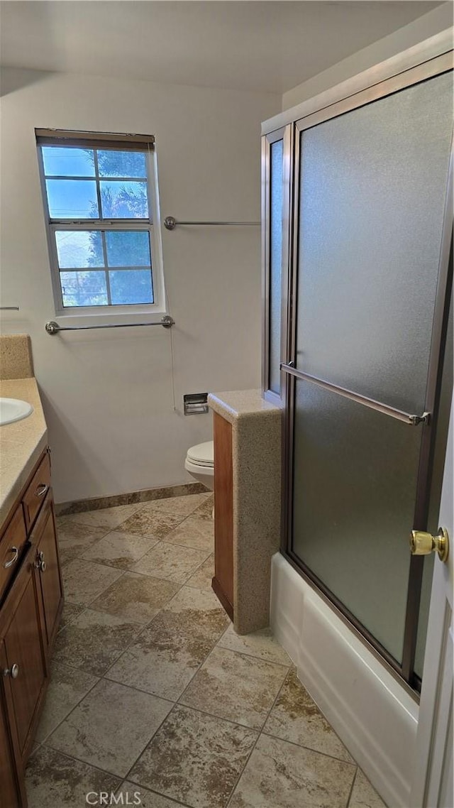 3930 Ironwood St, San Bernardino, CA 92404 - full bathroom with stone finish floor, vanity, toilet, combined bath / shower with glass door, and baseboards