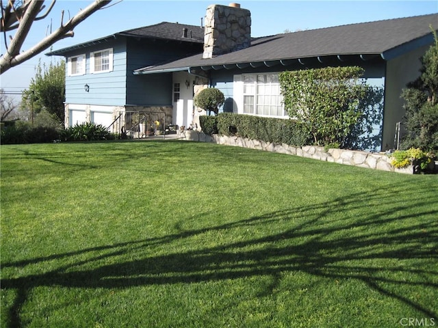 3930 Ironwood St, San Bernardino, CA 92404 - back of house featuring a yard, a garage, and a chimney