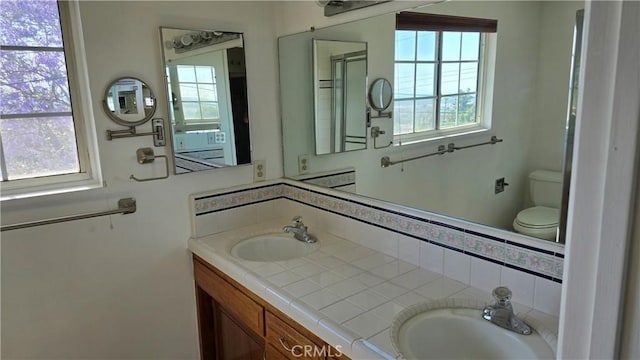 bathroom featuring vanity, toilet, a healthy amount of sunlight, and backsplash