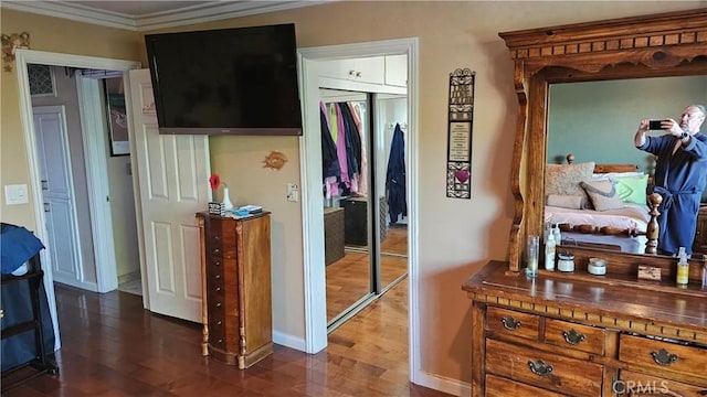 bedroom with dark wood-type flooring, a closet, and crown molding