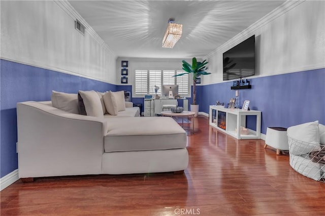 living room with crown molding, visible vents, and wood finished floors