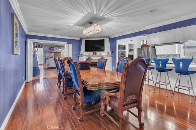 dining area featuring a notable chandelier, wood finished floors, baseboards, radiator, and crown molding