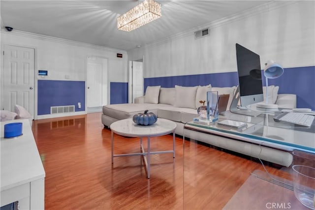 living room with ornamental molding, visible vents, a notable chandelier, and wood finished floors