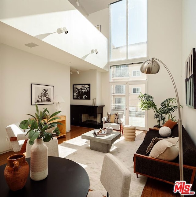 living room with wood-type flooring and a towering ceiling